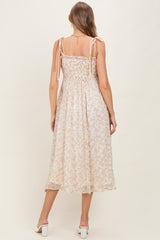 woman wearing a light floral print maternity dress with adjustable tie straps and a smocked back