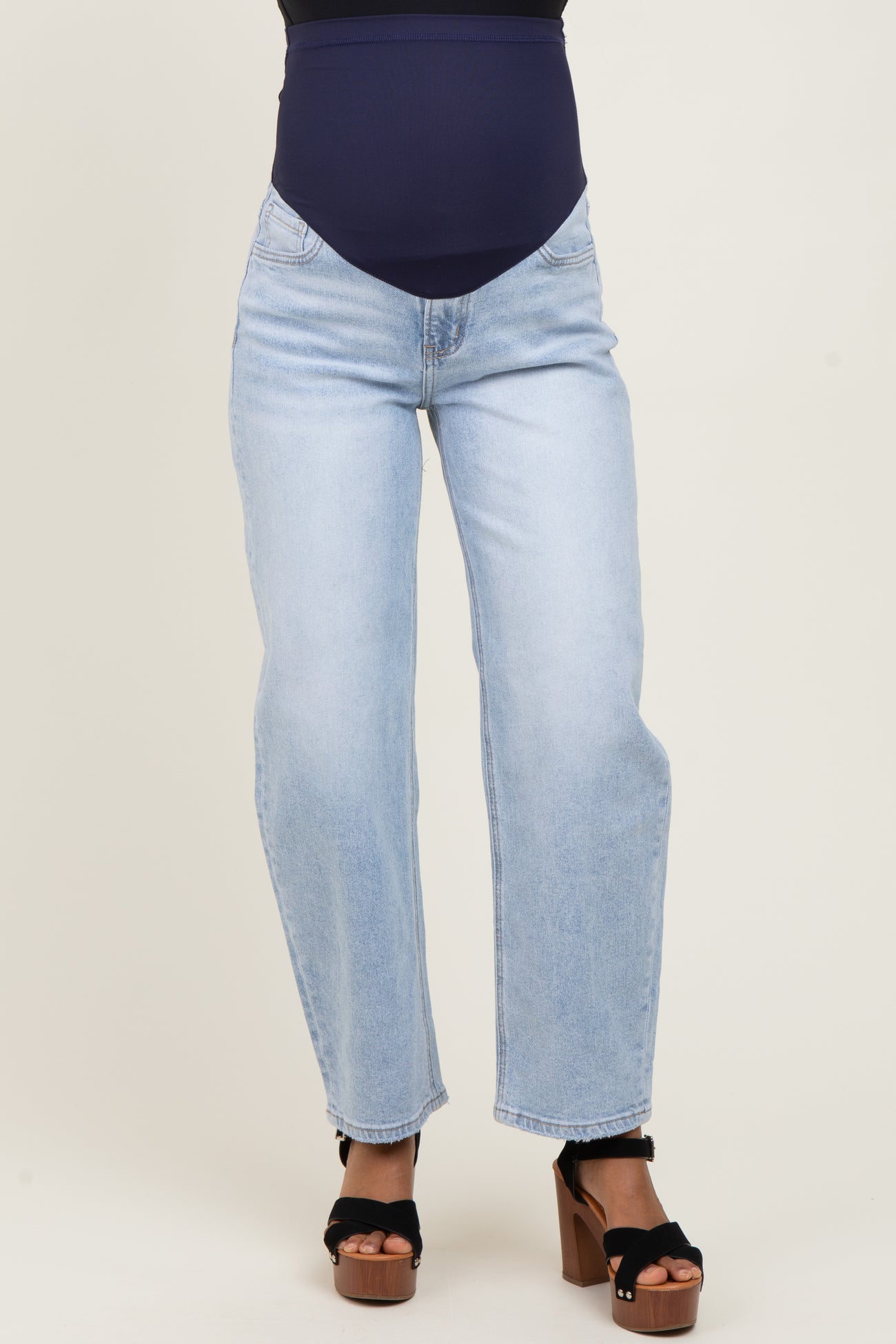 woman wearing a pair of light blue maternity jeans with a supportive belly band and black heeled sandals