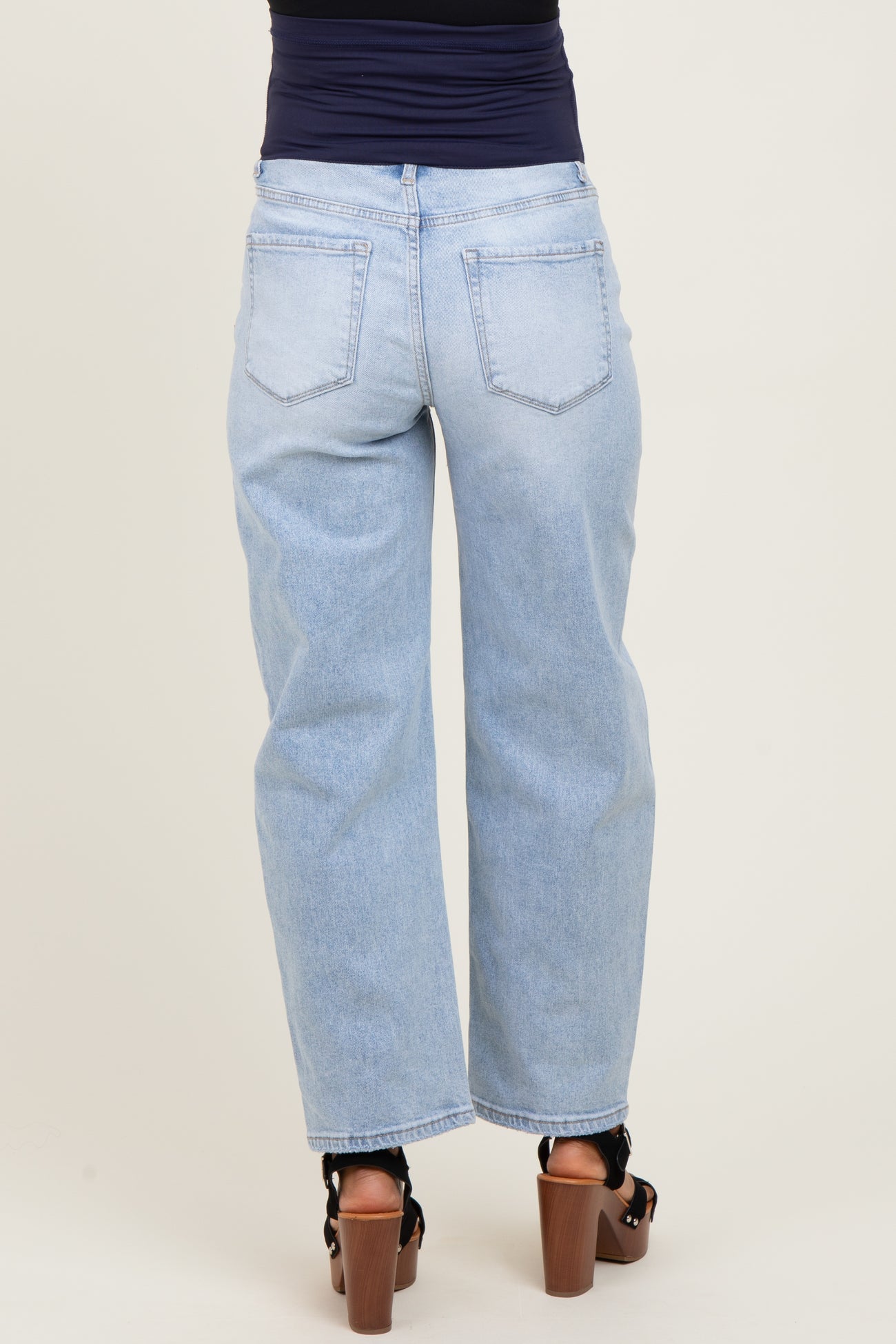woman wearing light wash maternity wide-leg jeans, view from the back, styled with chunky heels