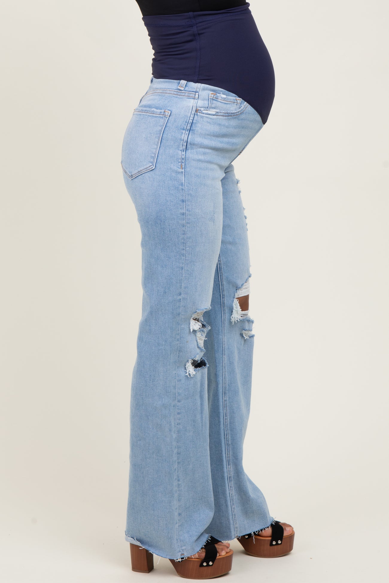 woman wearing a blue maternity jeans with distressed details and a visible baby bump