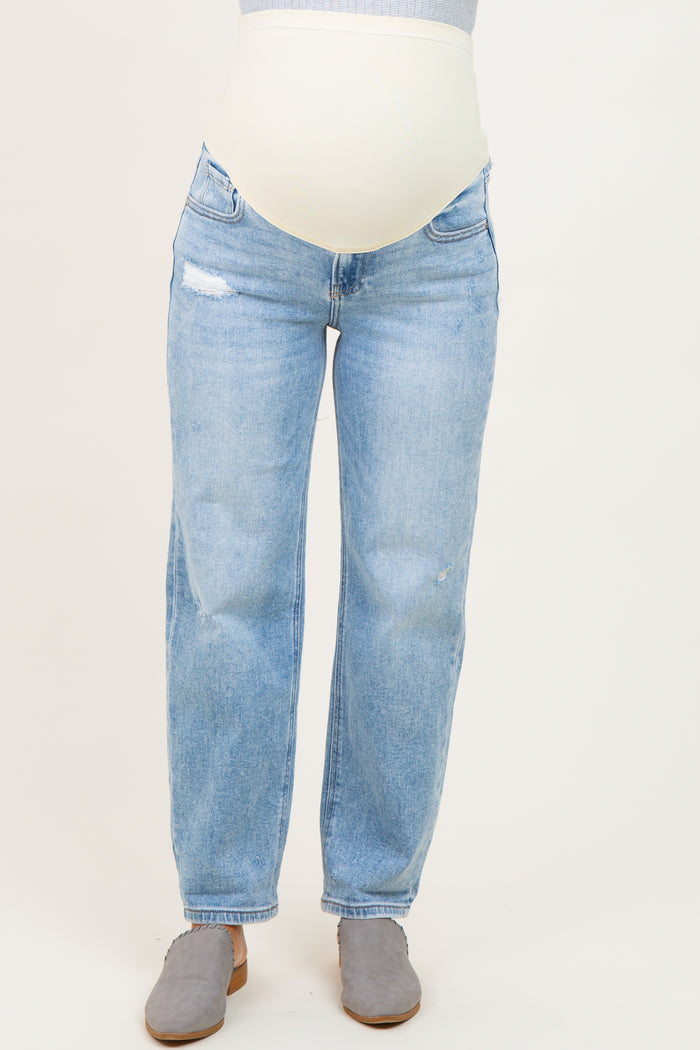 woman wearing light blue distressed maternity jeans with a supportive belly band and gray suede clogs