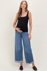 woman wearing a black maternity tank top and blue wide-leg jeans, displaying her baby bump