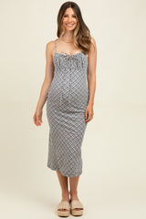 woman wearing a black and white patterned maternity dress with ruffled details and spaghetti straps, visible baby bump