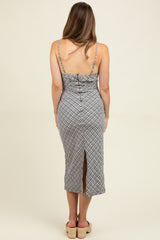 woman wearing a black and white patterned maternity dress with a fitted silhouette and a thigh-high slit at the back