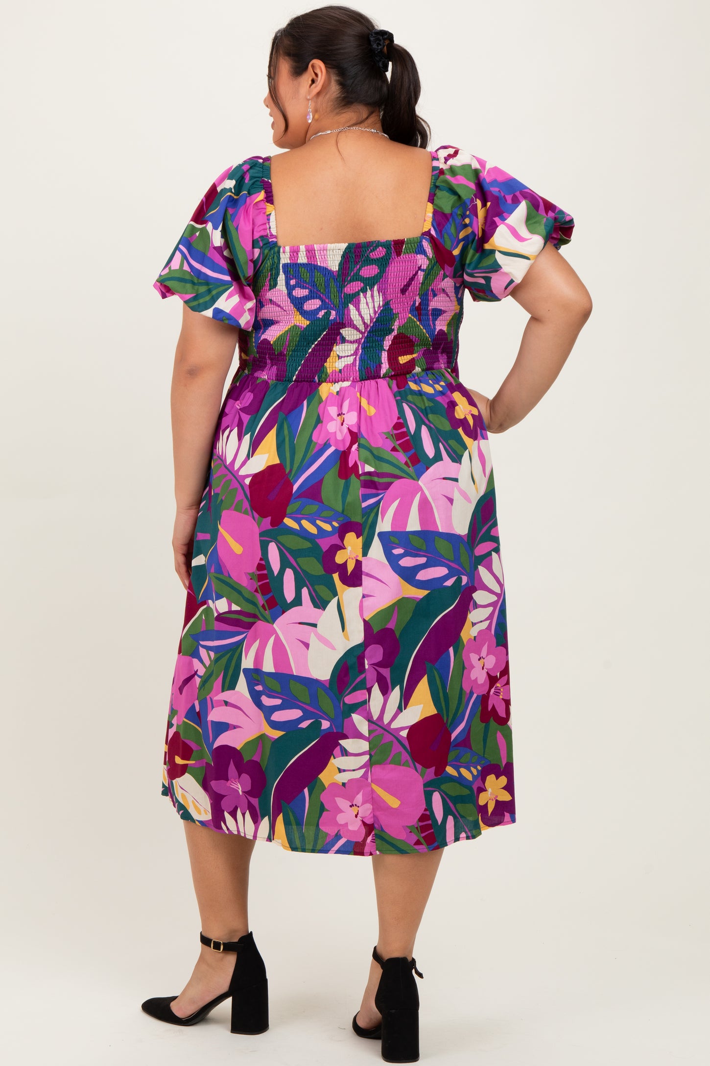 woman wearing a colorful floral print plus size dress with puffed sleeves, shown from the back