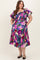 woman wearing a colorful floral print maternity dress with ruffled sleeves and pockets, showcasing a baby bump
