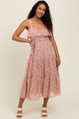 woman wearing a floral pink sundress with ruffled straps and a tiered skirt, standing and smiling