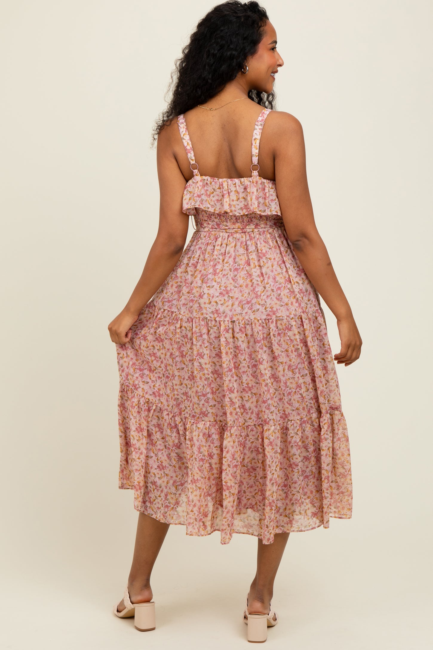 woman wearing a pink floral midi dress with a ruffled bodice and tiered skirt, seen from the back