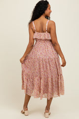 woman wearing a pink floral midi dress with a ruffled bodice and tiered skirt, seen from the back