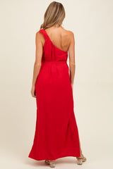 woman wearing a red one-shoulder maternity maxi dress with a tie detail at the shoulder and side slits