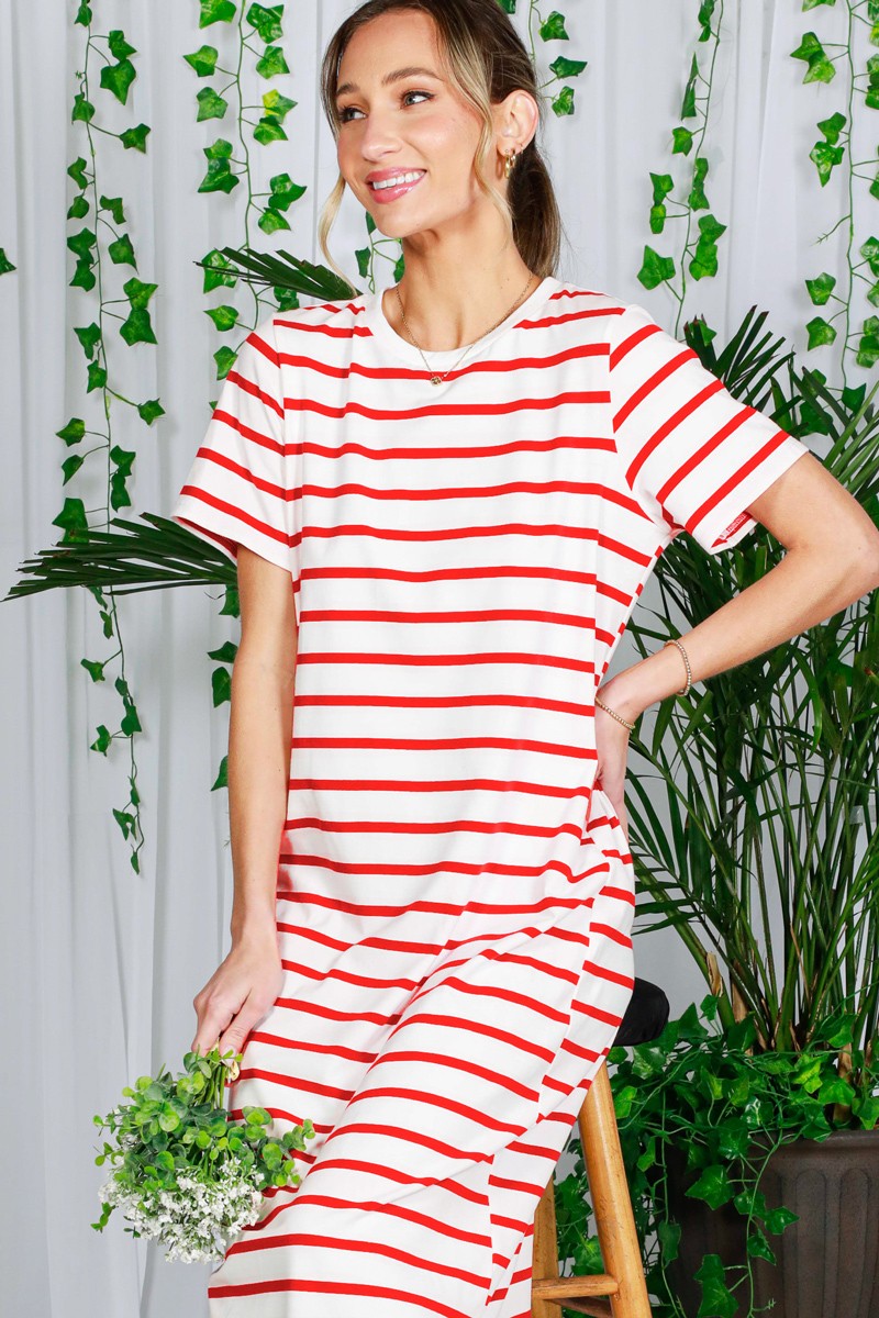woman wearing a red and white striped oversized t-shirt dress while sitting and holding a small bouquet of flowers