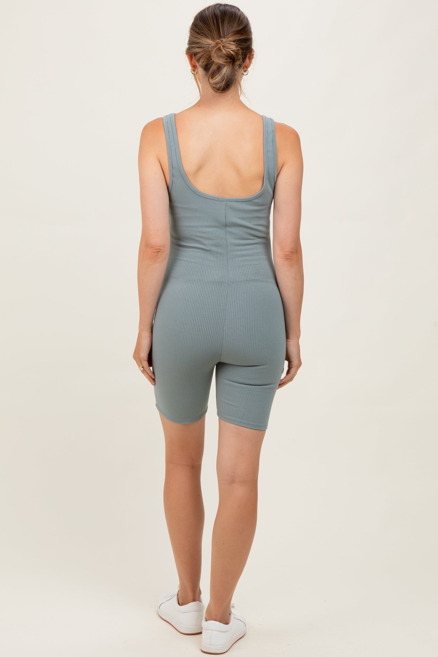 woman wearing a green ribbed maternity romper with fitted shorts, showing the back view