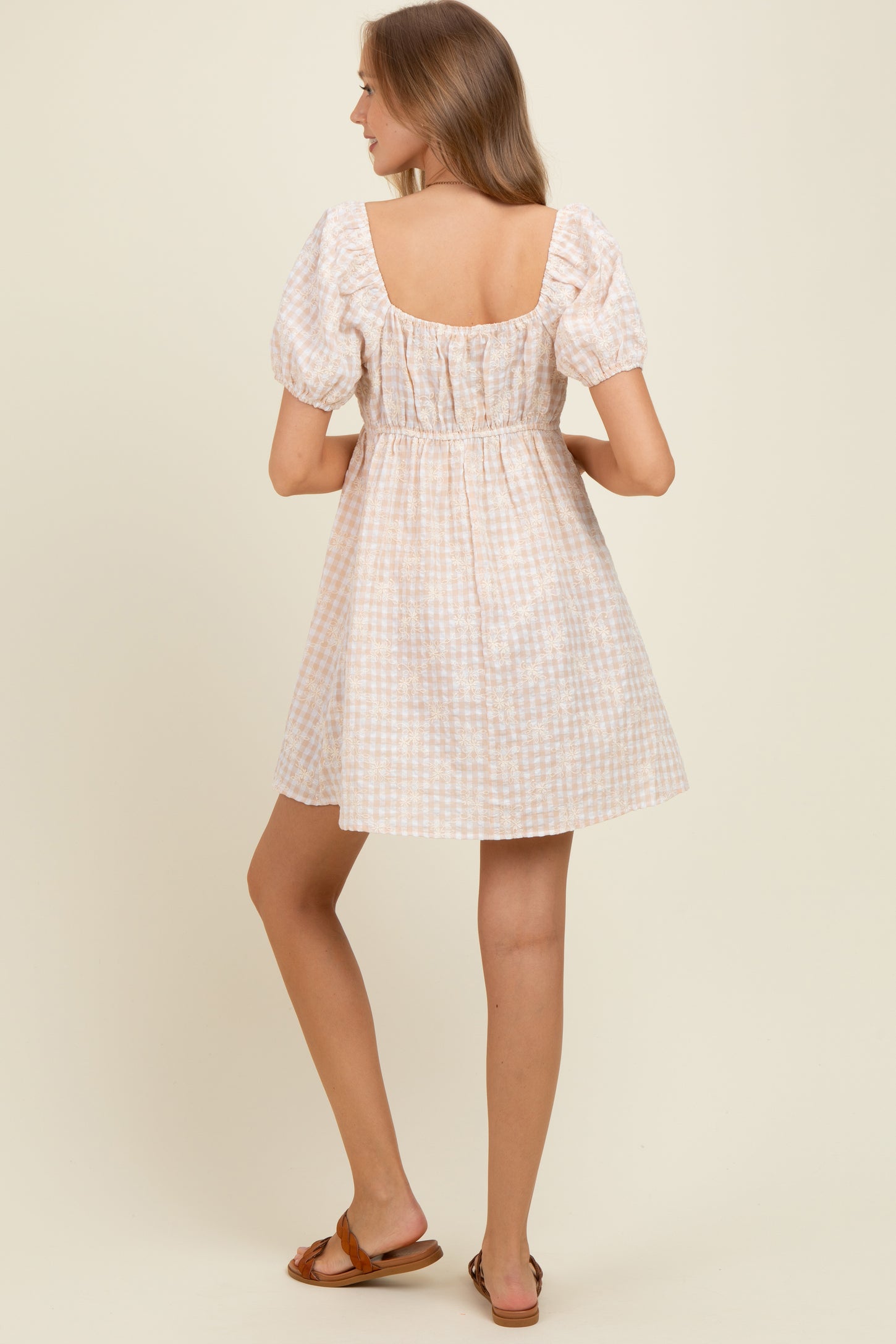 woman wearing a pastel checkered short sleeve maternity dress with a square neckline and gathered waist, showing her back