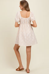 woman wearing a pastel checkered short sleeve maternity dress with a square neckline and gathered waist, showing her back