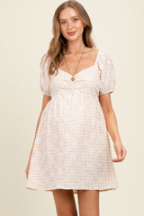 woman wearing a light pink checked maternity dress with puff sleeves and a baby bump visible