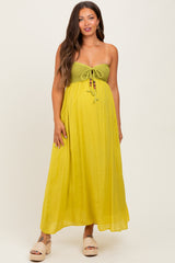 woman wearing a yellow maternity maxi dress with a crocheted bodice and tie detail, showing her baby bump