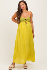 woman wearing a yellow maternity maxi dress with a crochet bodice and tie detailing, showcasing her baby bump