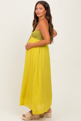 woman wearing a yellow maternity maxi dress with a smocked bodice and flowing skirt, showing her baby bump