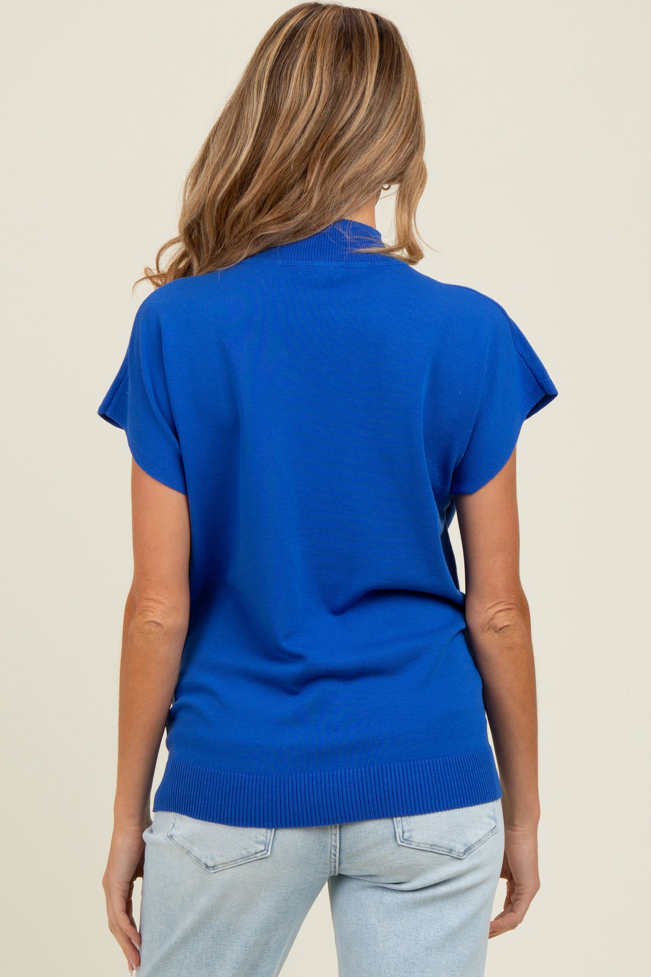 woman wearing a bright blue short sleeve maternity top, viewed from the back