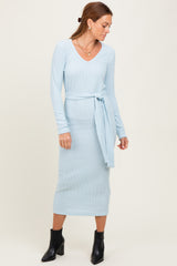 woman wearing a light blue ribbed long sleeve midi dress with a tie belt and black ankle boots