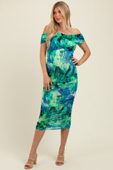 woman wearing a colorful off-the-shoulder maternity dress that highlights her baby bump