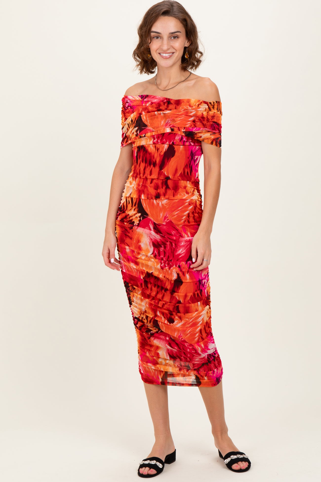 woman wearing a colorful off-the-shoulder midi dress with a floral pattern and a fitted silhouette