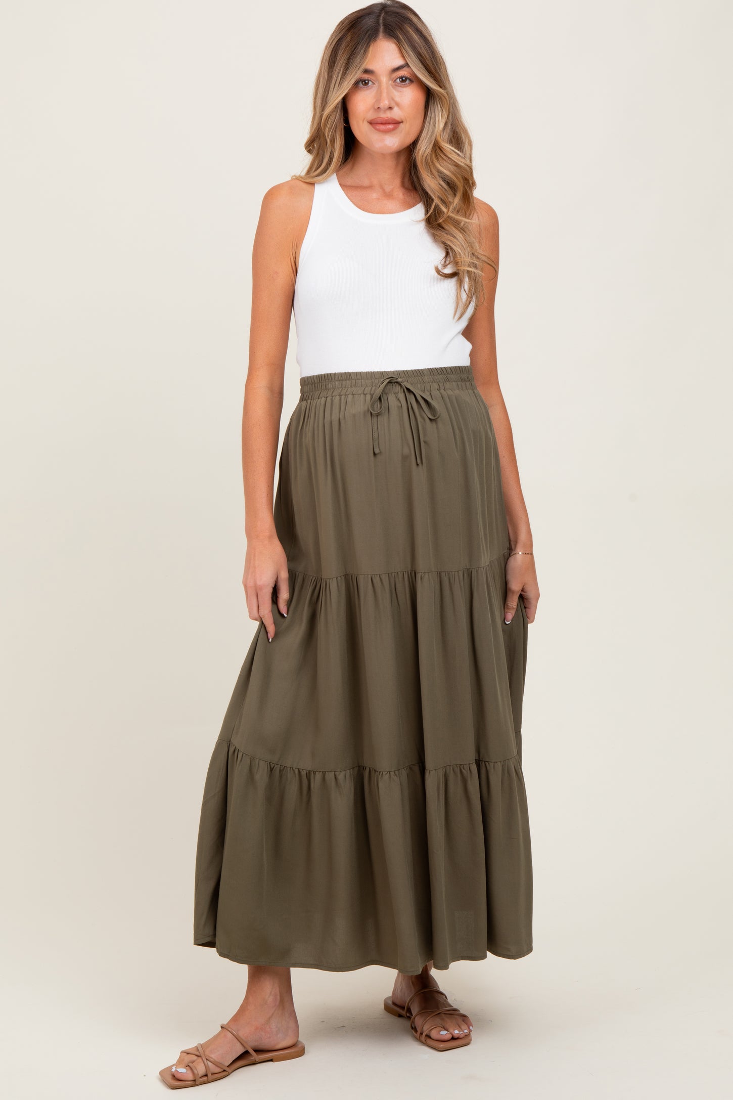 woman wearing a white tank top and an olive green maternity maxi skirt with tiered design and elastic waist