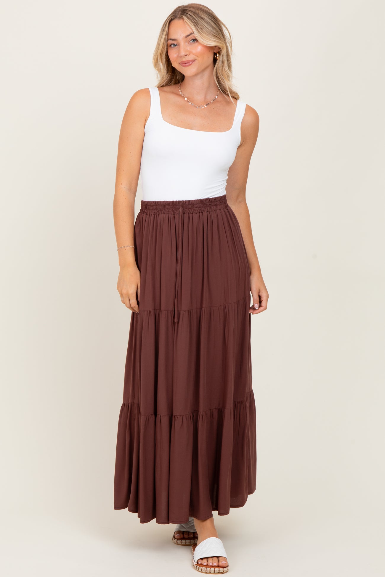 woman wearing a white square neck tank top and a brown tiered maxi skirt