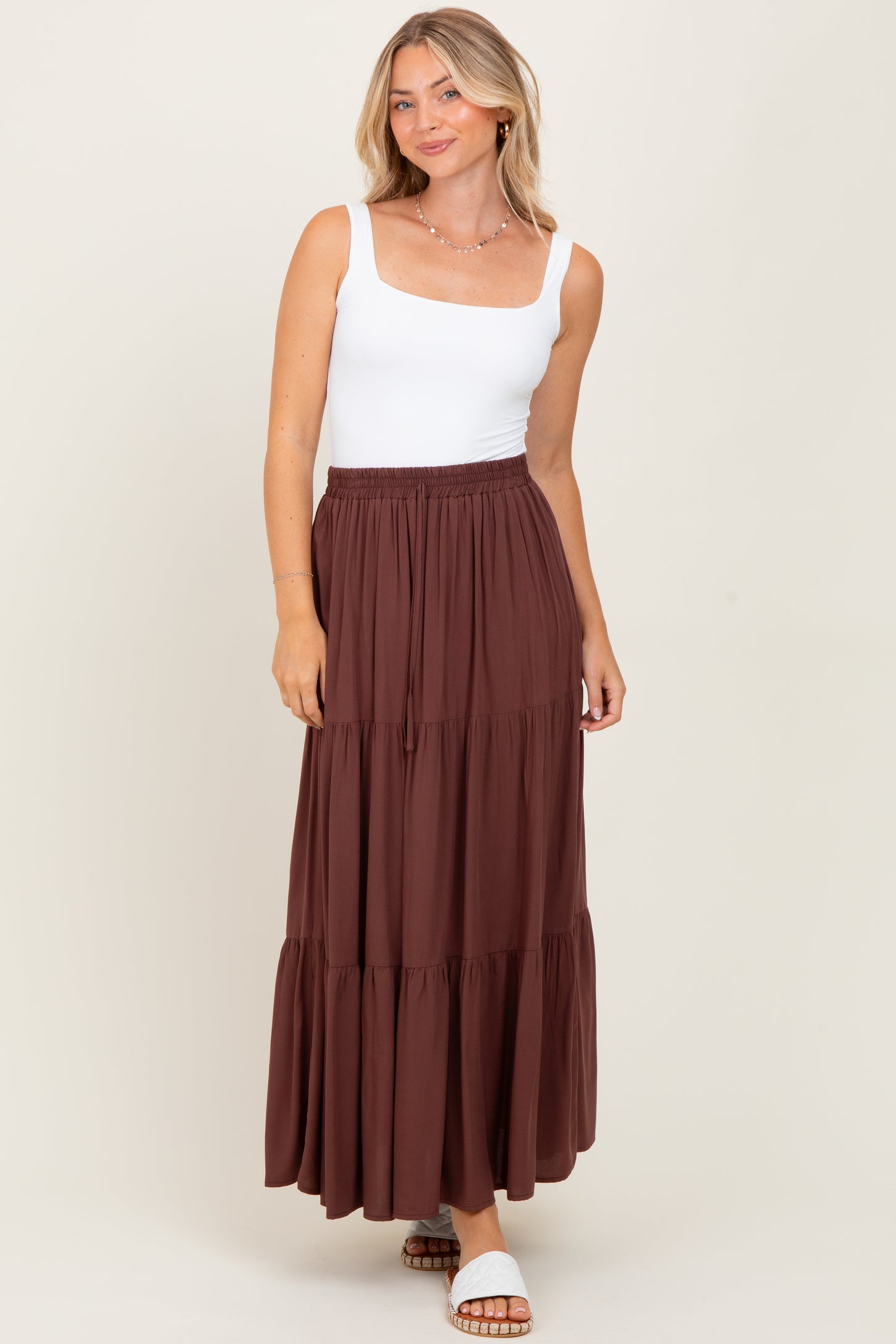 woman wearing a white square neck tank top and a brown tiered maxi skirt