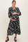 woman wearing a floral black maternity dress with a v-neck and puff sleeves, holding her baby bump