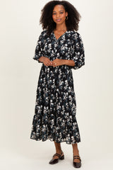 woman wearing a black floral midi dress with a v-neckline and puff sleeves, standing on a neutral background