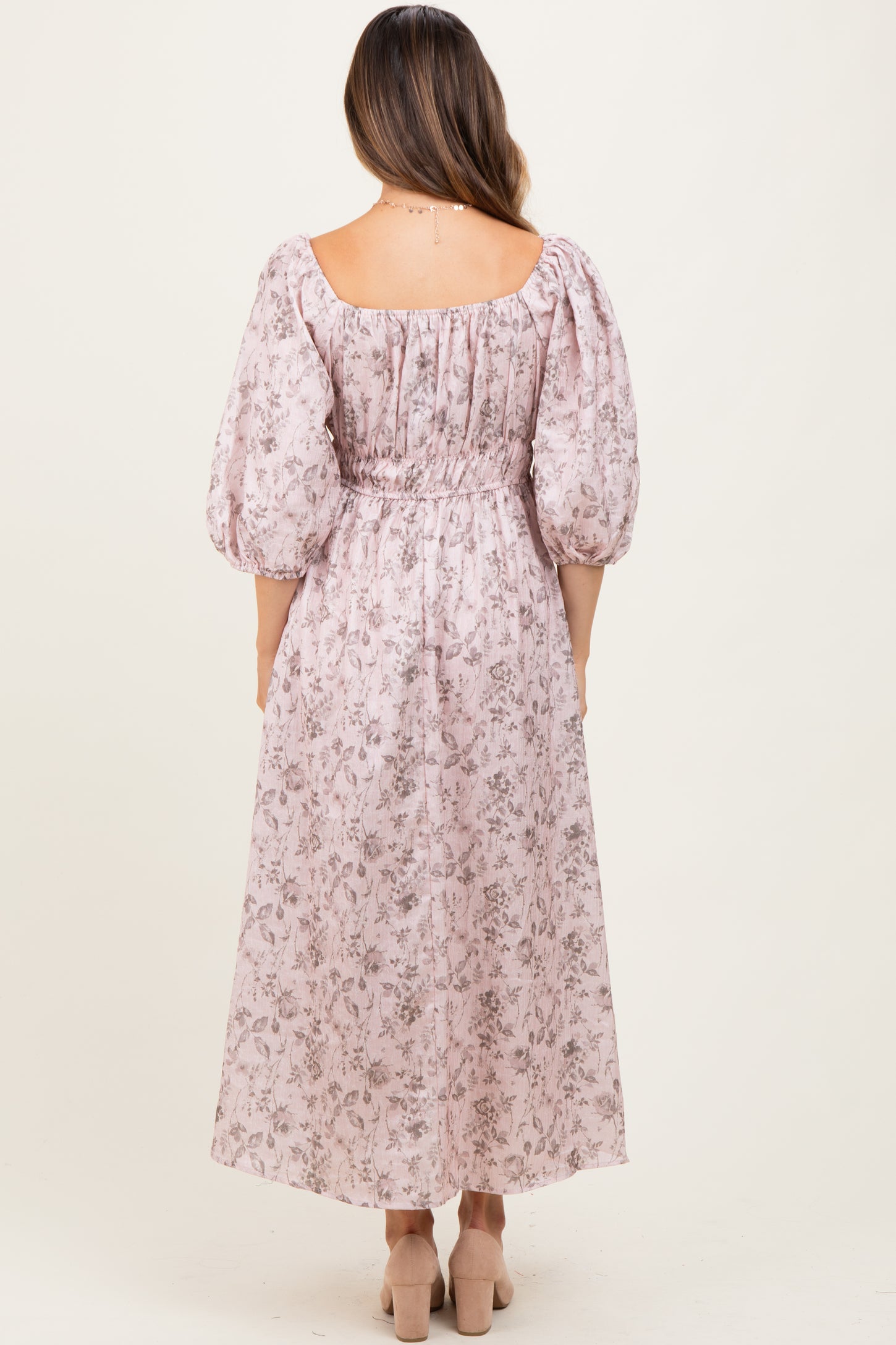 woman wearing a pink floral maternity dress with a cinched waist and puff sleeves, showcasing a baby bump from the back