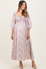 woman wearing a pink floral maternity maxi dress with puff sleeves and a visible baby bump