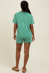 woman wearing a green striped short sleeve top and matching shorts, standing with her back to the camera