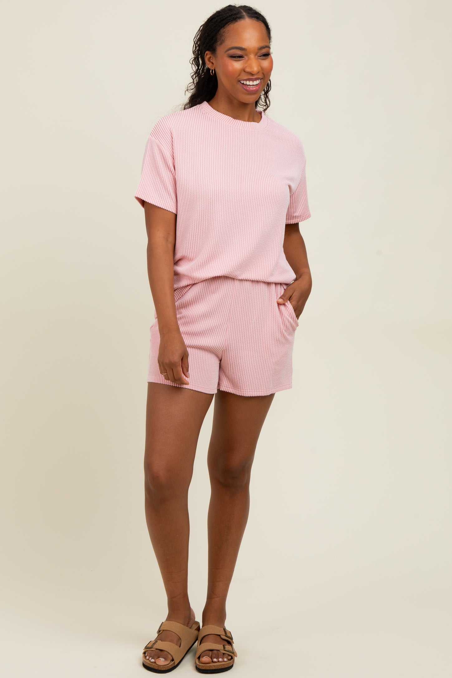 woman wearing a pink and white striped short sleeve top and matching shorts with pockets