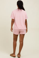 woman wearing a pink and white striped short sleeve top and matching shorts, standing with her back to the camera