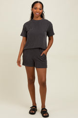 woman wearing a black and white striped short sleeve top and matching shorts, standing with hands in pockets