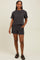 woman wearing a black and white striped short sleeve top and matching shorts, standing with hands in pockets