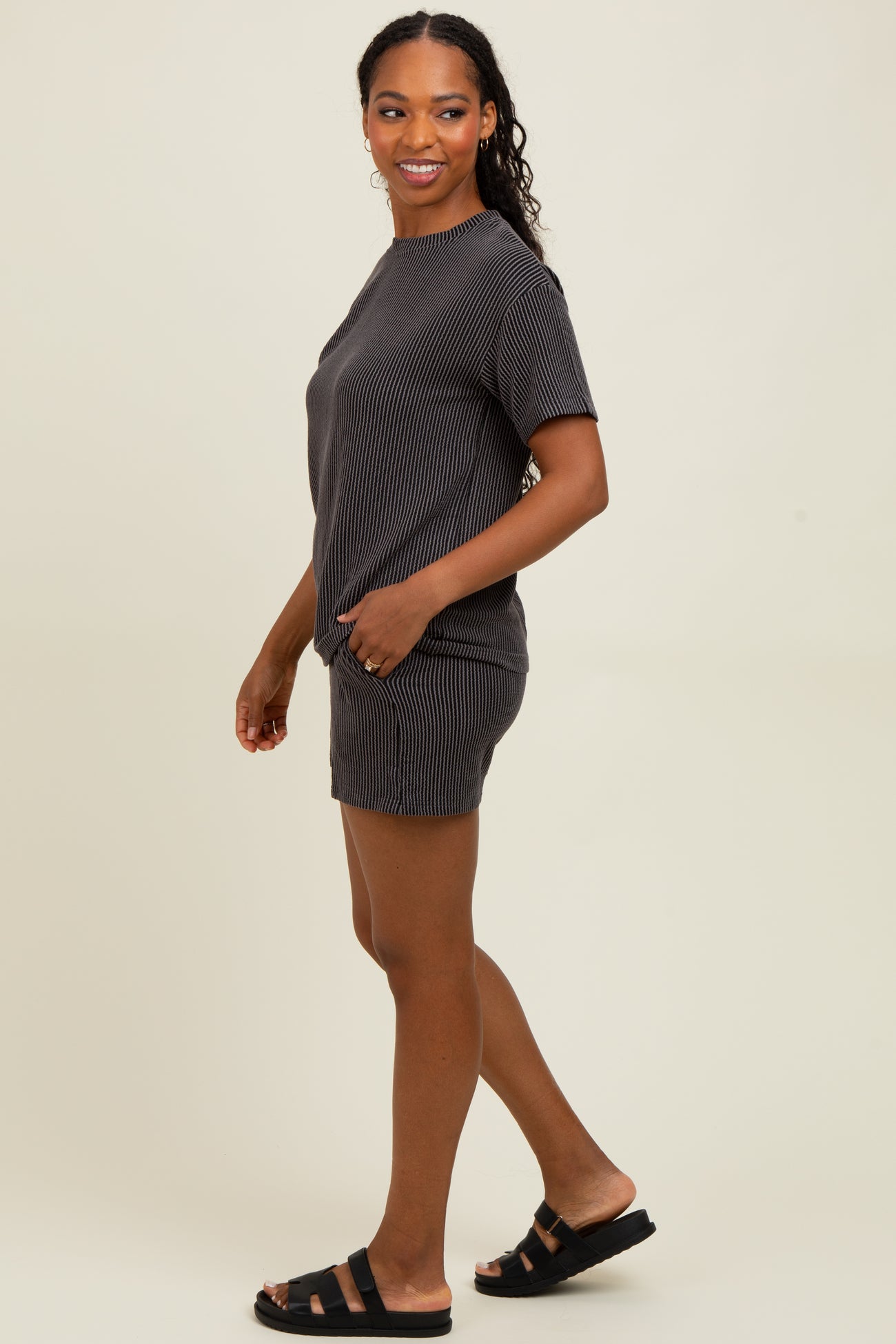 woman wearing a gray and white striped short sleeve top and matching shorts, standing and smiling