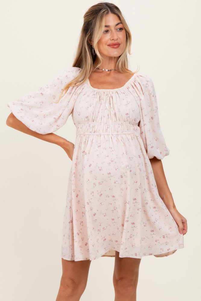 woman wearing a pink floral maternity dress with puff sleeves, showcasing a baby bump