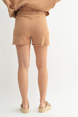 woman wearing tan knitted shorts with a relaxed fit and raw hem, shown from the back