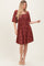 woman wearing a rust-colored floral print short sleeve dress with a square neckline and gathered waist