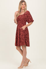 woman wearing a rust-colored floral print short sleeve dress with an elastic waist and pockets