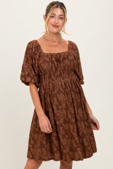 woman wearing a brown maternity dress with a square neckline and puff sleeves, featuring a gathered waistline