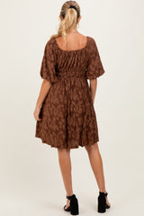 woman wearing a brown patterned maternity dress with puff sleeves and a fitted waist, showing a baby bump from the back