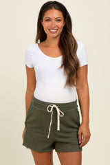 woman wearing a white scoop neck maternity top and green ribbed maternity shorts with a drawstring waistband
