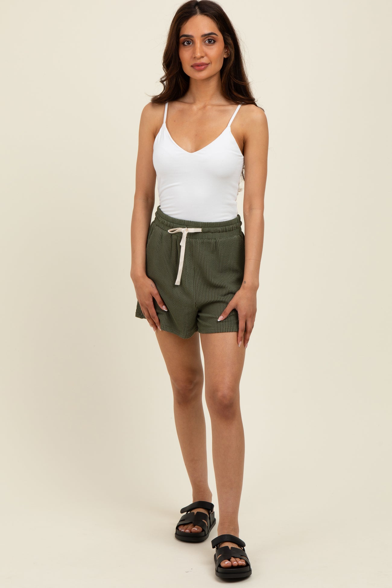 woman wearing a white spaghetti strap tank top and green striped shorts with a drawstring waist