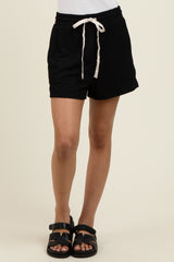 woman wearing black ribbed drawstring shorts with a white tie detail and black sandals