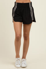 woman wearing black athletic shorts with white side stripes and an elastic waistband