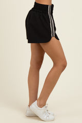 woman wearing black athletic shorts with white side stripes and white sneakers